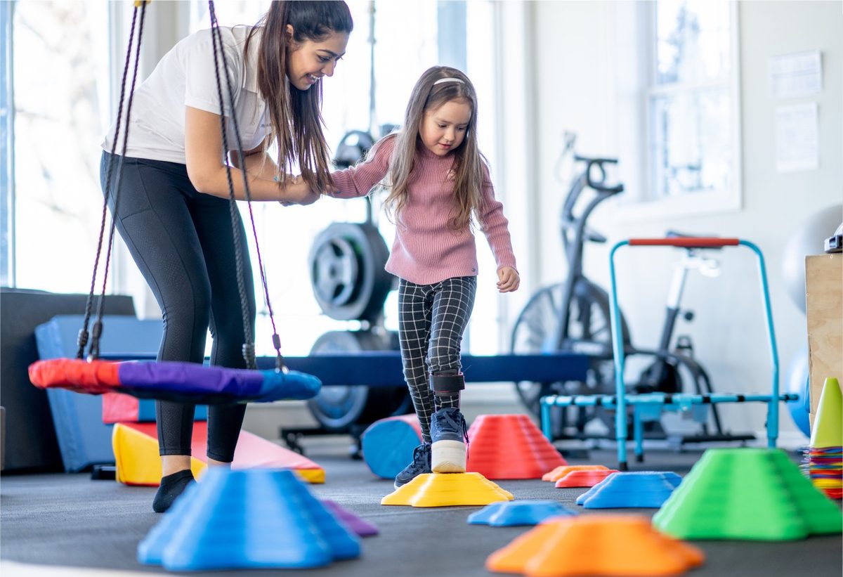 Occupational therapist guiding a girl across sensory stepping stones